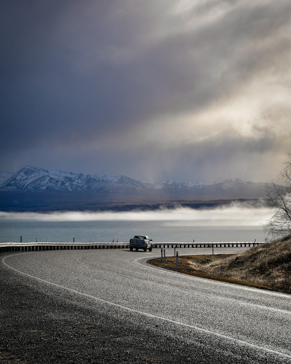 black car on road near body of water during daytime