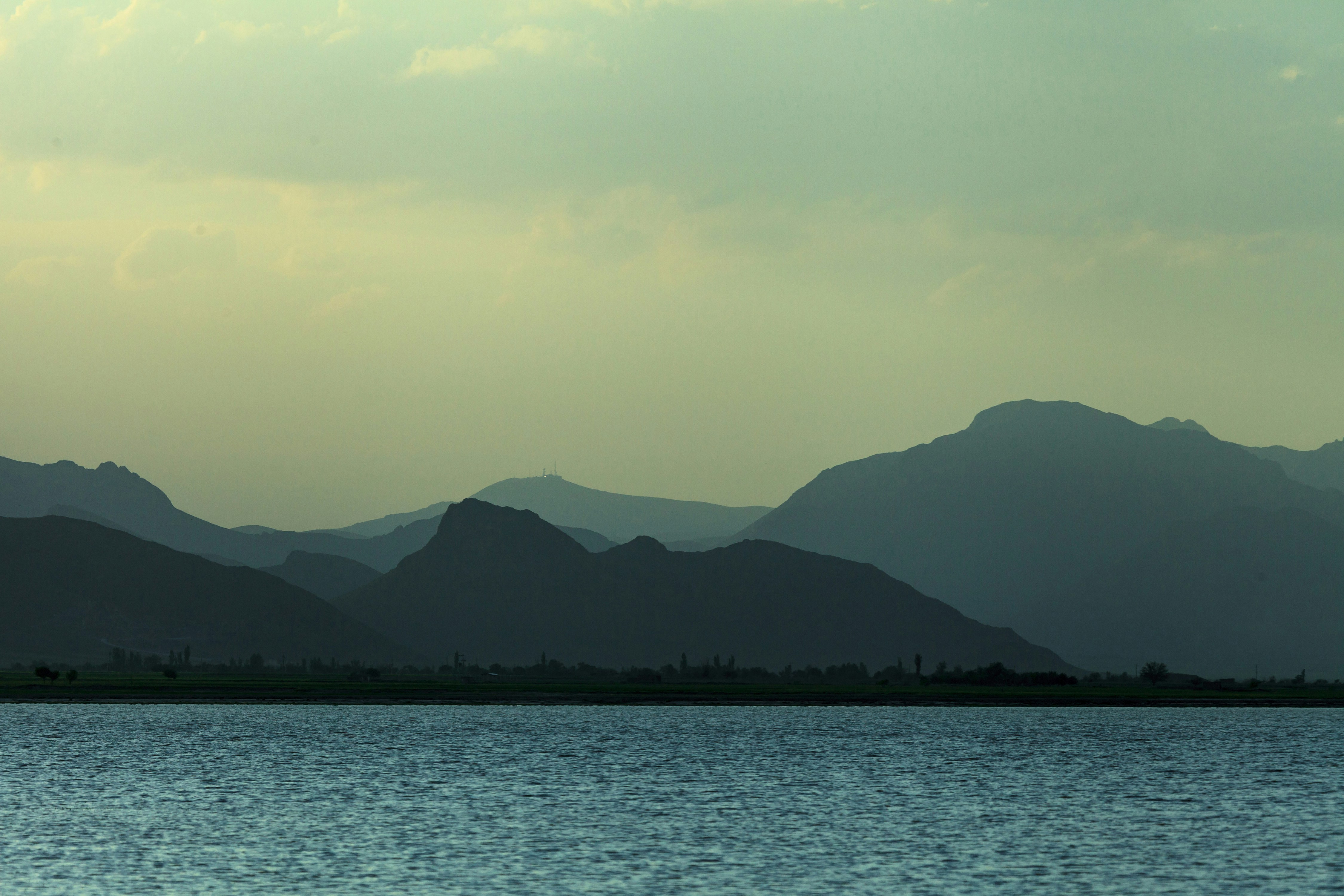 body of water near mountain during daytime