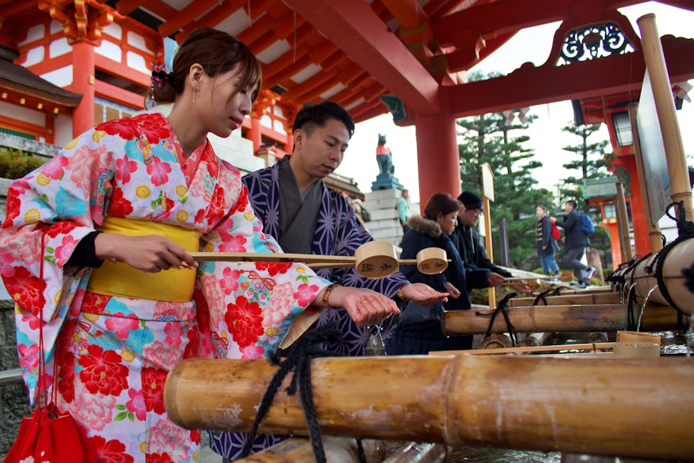 woman in white pink and green floral kimono holding brown wooden drum