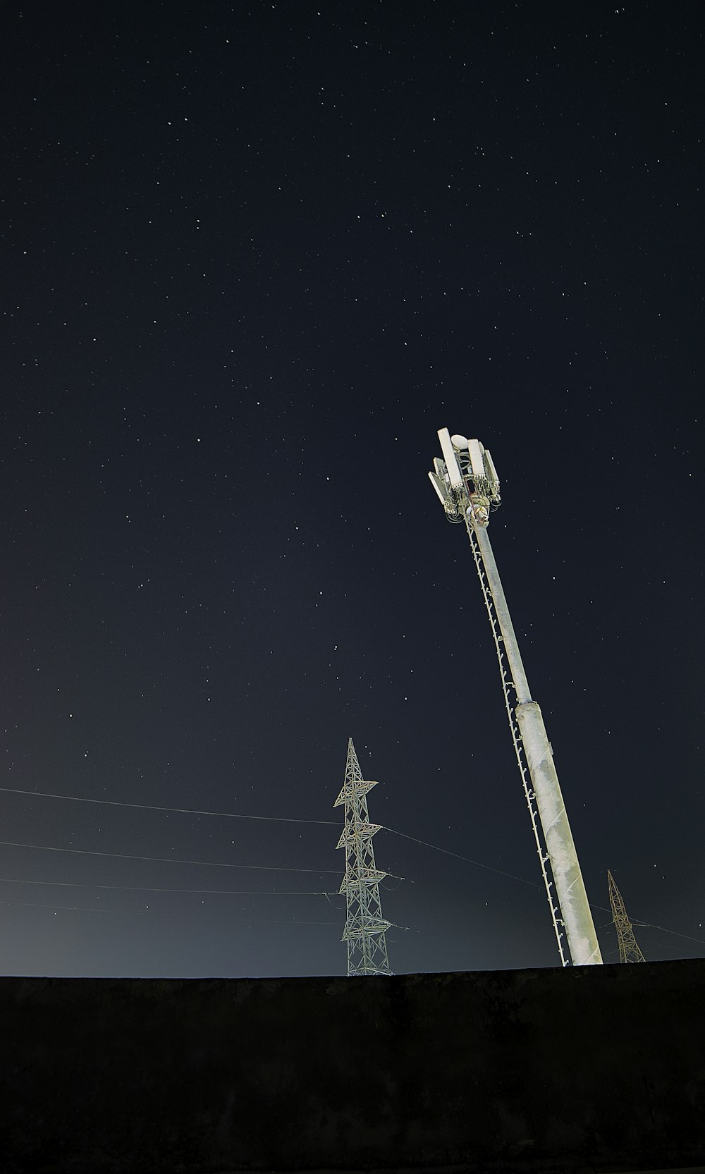 Torre satelital blanca y negra bajo cielo negro