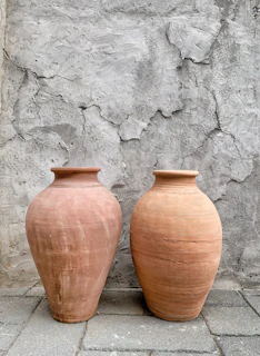 Vintage-style cement pots with intricate patterns, placed on a rustic table.