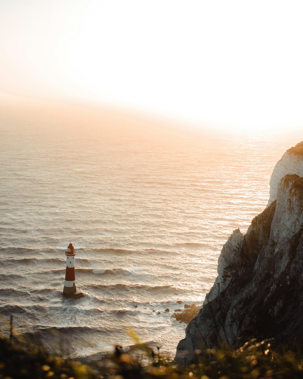 a red and white lighthouse sitting on top of a cliff