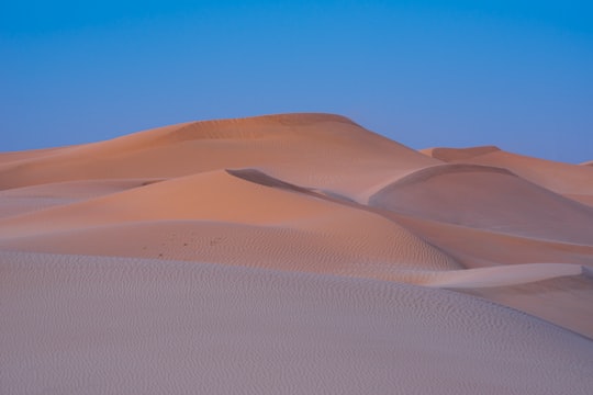brown desert under blue sky during daytime in Abu Dhabi - United Arab Emirates United Arab Emirates
