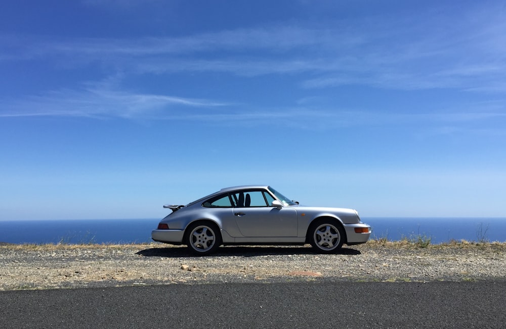 cupê branco mercedes benz na areia cinza sob o céu azul durante o dia