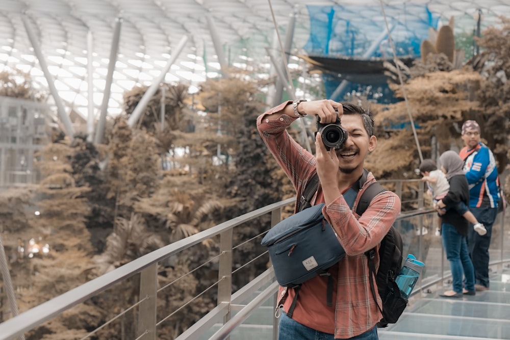 man in black and red backpack taking photo of trees during daytime