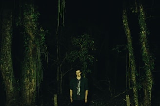 A rugged survivor searching through a dense forest for supplies at dusk.