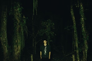 A shadowy figure standing near the edge of the dense North Georgia forest under a full moon.