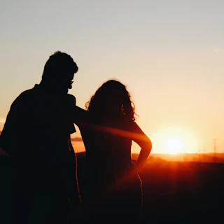 A silhouette of Gilson and Daniely against a sunset sky, symbolizing hope and new beginnings.