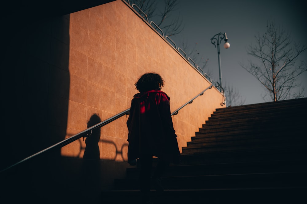 woman in black and red coat walking on staircase