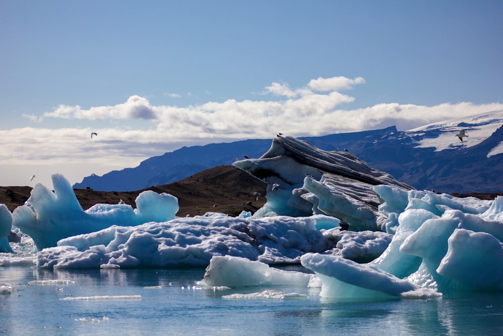 ice on body of water near mountain under blue sky during daytime