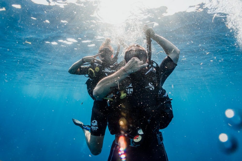 Hombre con traje de neopreno negro buceando en el agua