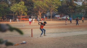 man in black shirt and brown pants playing baseball during daytime