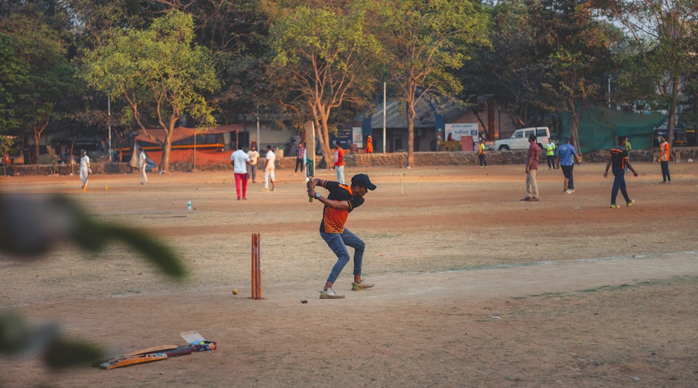 man in black shirt and brown pants playing baseball during daytime
