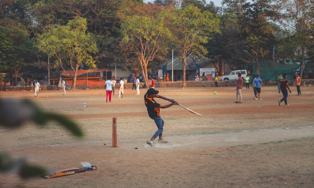 man in red jacket and blue denim jeans playing baseball during daytime