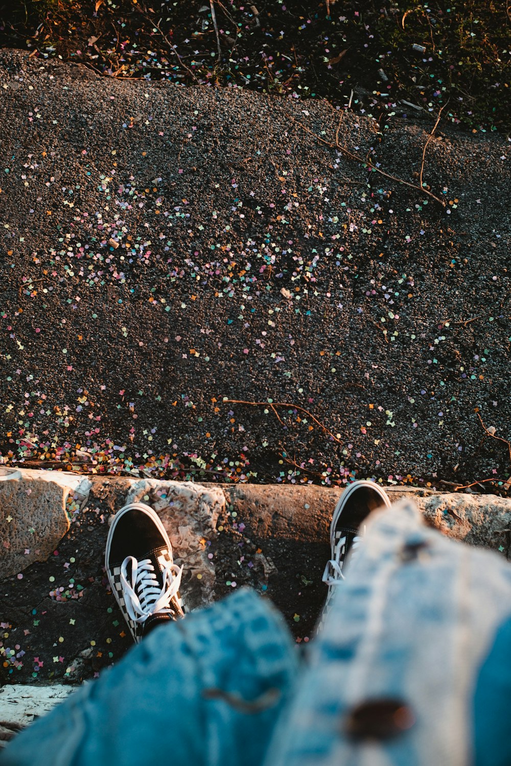 person in blue denim jeans and black and white sneakers standing on brown concrete pavement