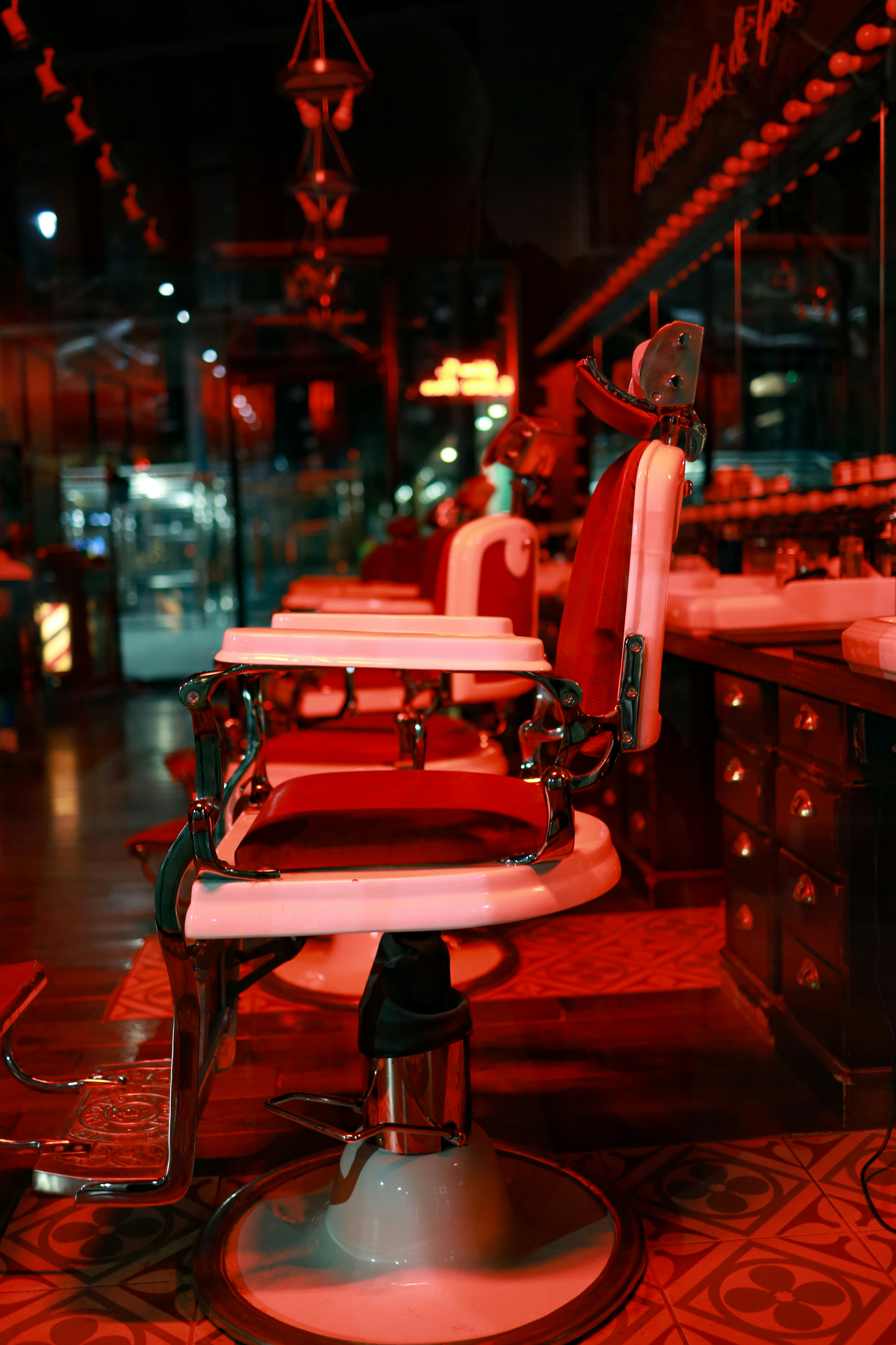 Luxurious dark barbershop interior with vintage leather chairs, warm ambient lighting, and high-end grooming tools