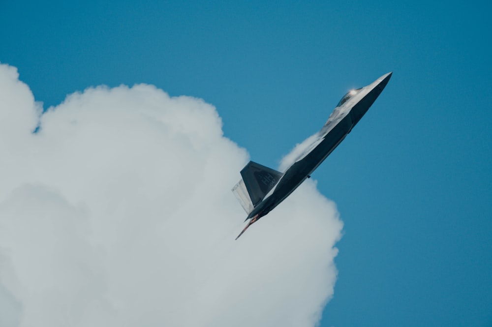 a fighter jet flying through a cloudy blue sky