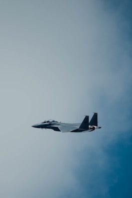 Close-up of a sleek modern fighter jet soaring through a clear blue sky.