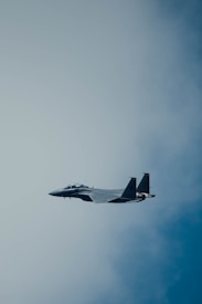 A military fighter jet flies through a clear blue sky, displaying its sleek, aerodynamic design and powerful engines.
