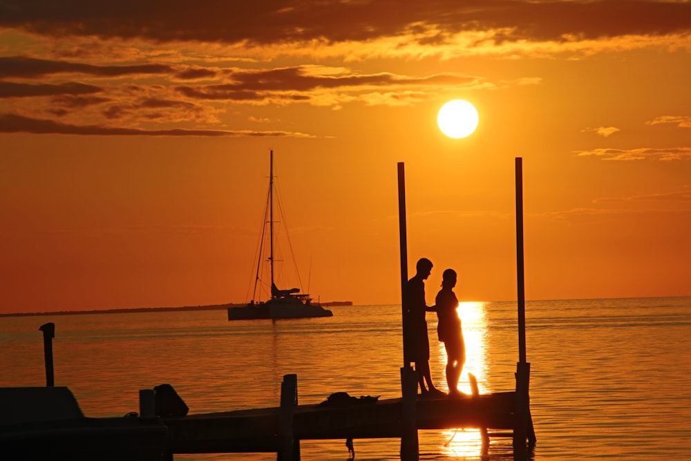 silhouette of 2 people on boat during sunset