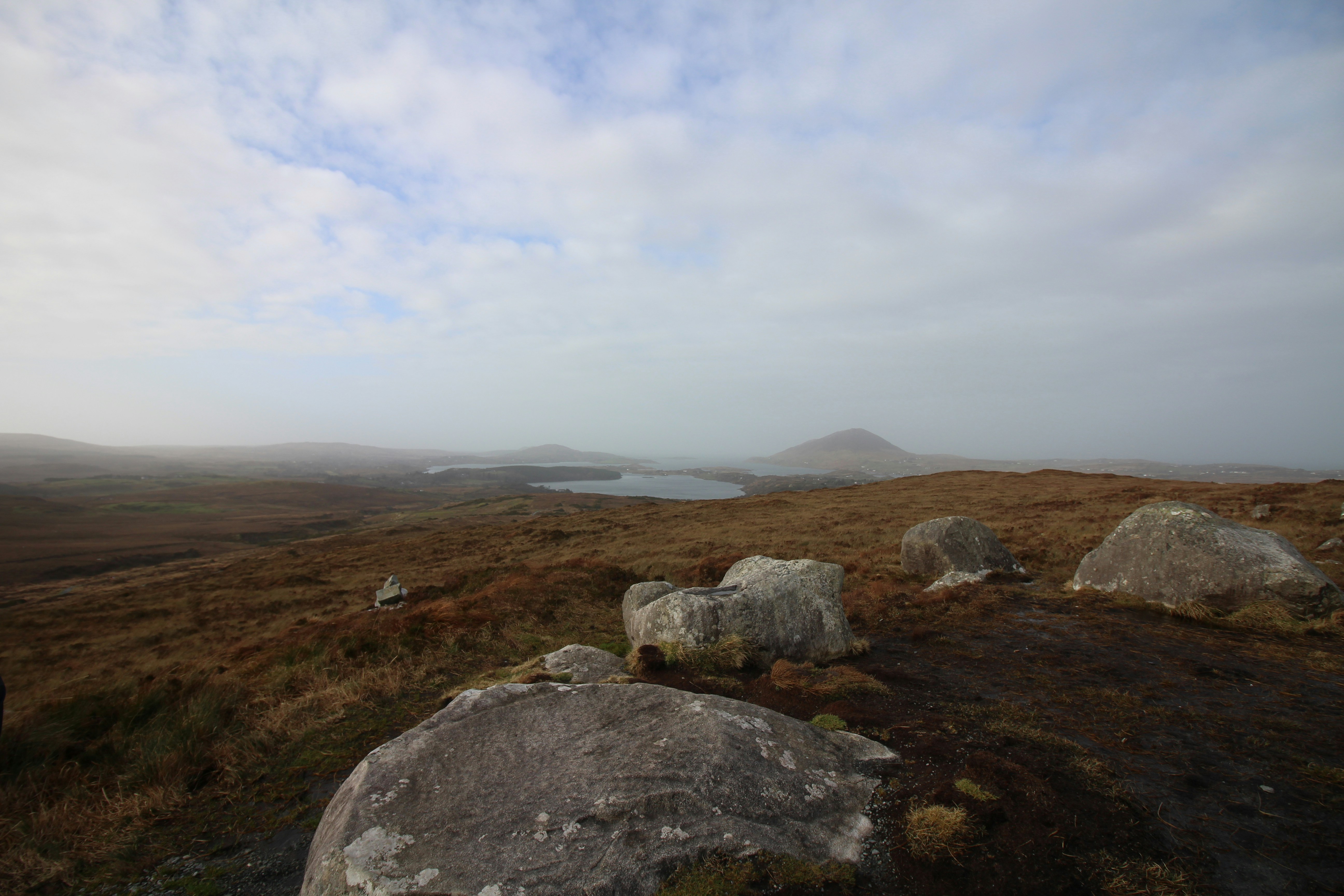 gray rock formation on brown grass field under white cloudy sky during daytime, 