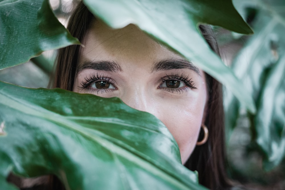 woman covering her face with green leaf