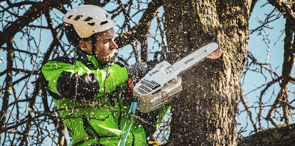 man in green jacket playing white and black snow blower