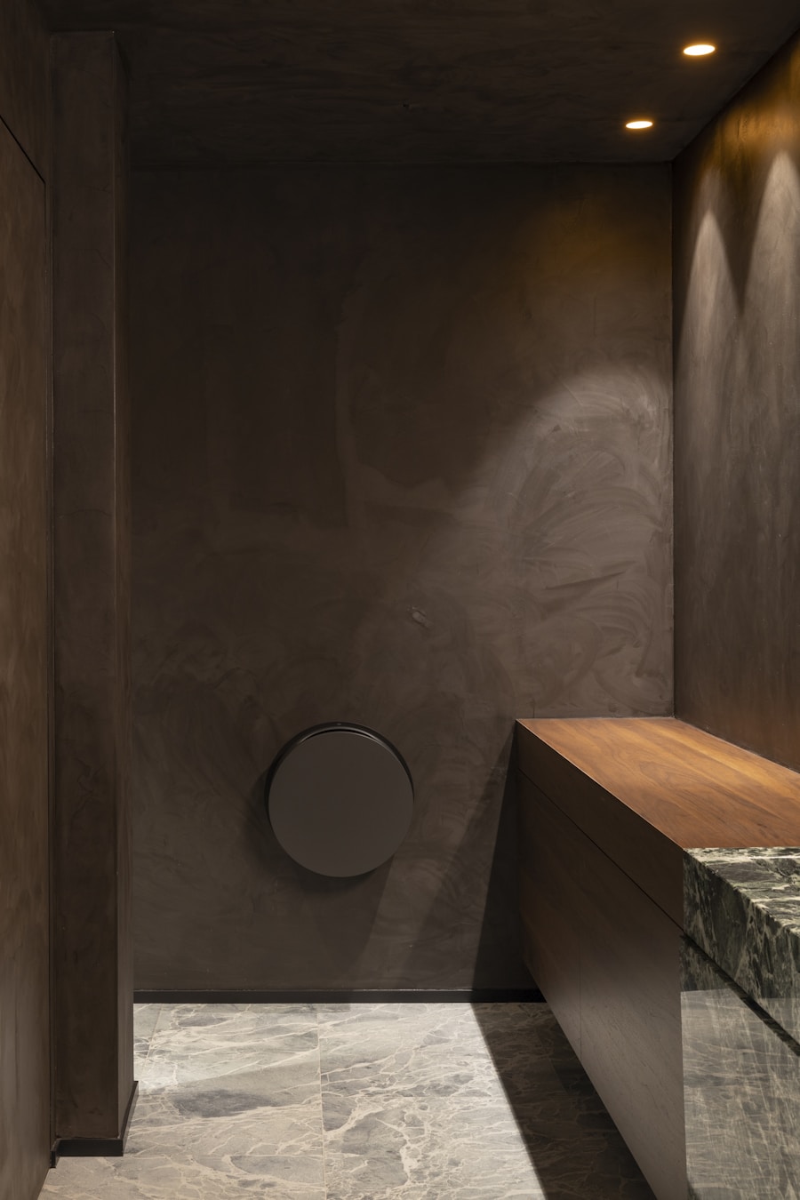 Quiet corridor with warm plaster walls, a wood bench and marble flooring