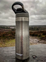 A pure copper bottle filled with water, condensation droplets visible, set against a royal black background.