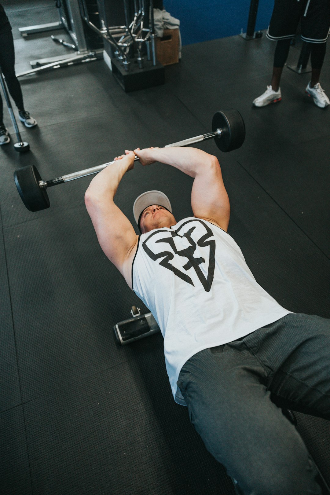 man in white tank top and black denim jeans lying on black exercise mat