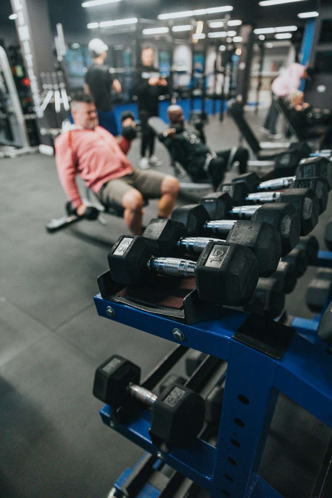 man in white shirt and black pants sitting on black and blue exercise equipment