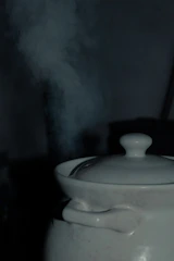 Close-up of a ceramic pot on an induction cooktop with steam rising