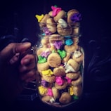 A cheerful hand holding a jar filled with agenticlemon sweets.