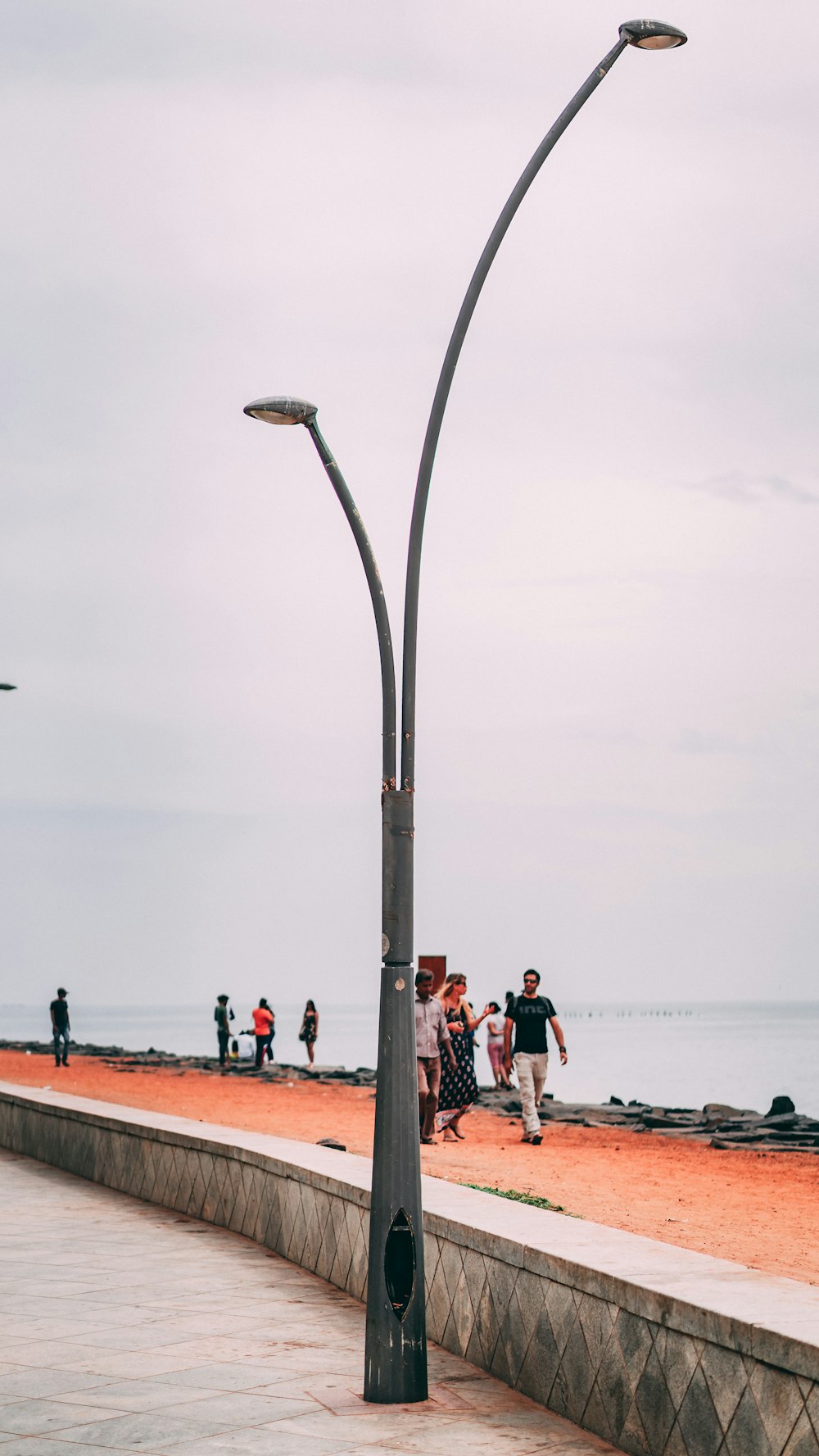 um grupo de pessoas caminhando em uma praia ao lado de um poste de luz