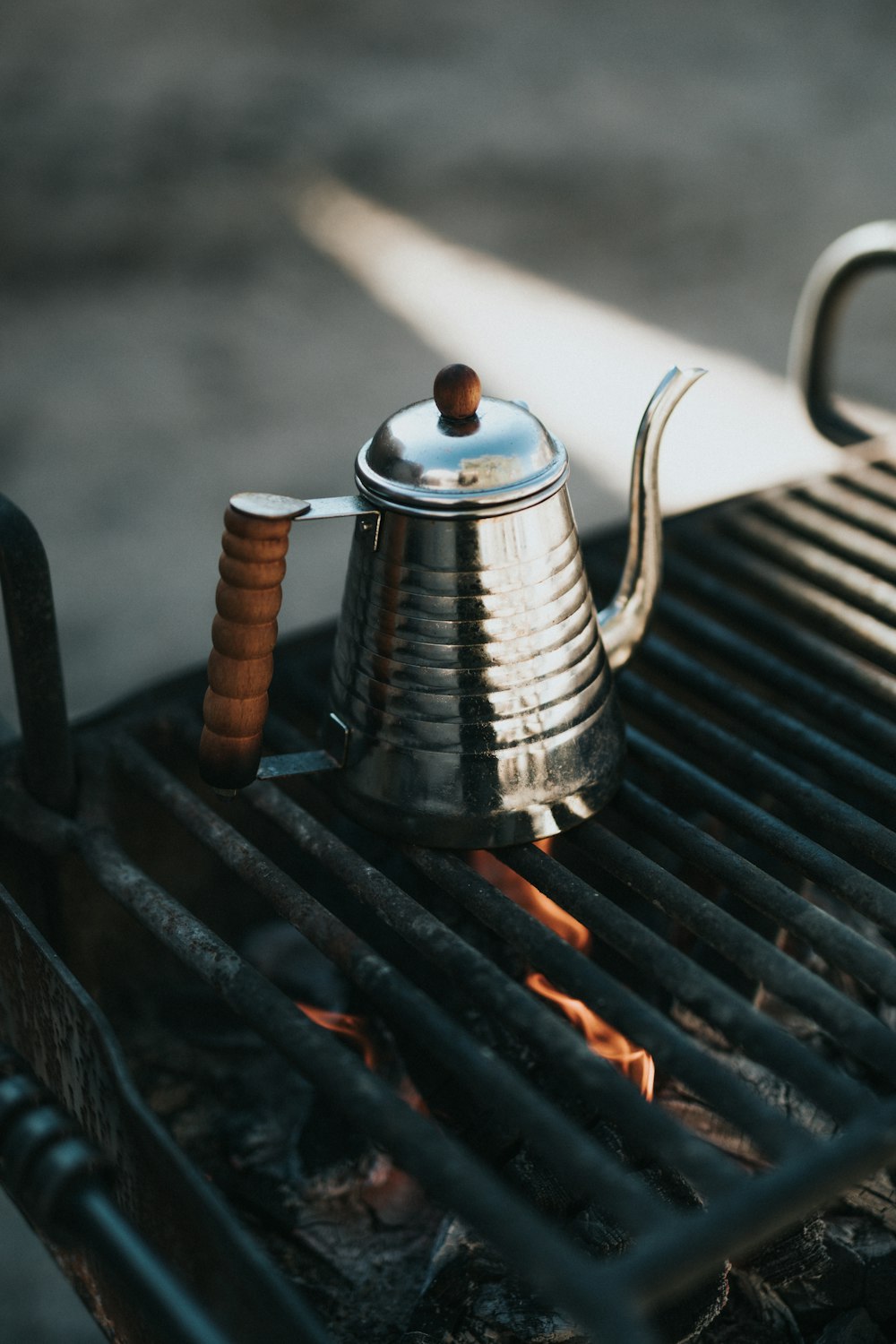 stainless steel teapot on black metal grill