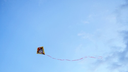 A colorful rocket toy soaring against a bright blue sky.