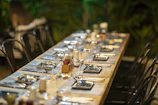 A long wooden table set outdoors with vibrant, colorful dishes ready for a feast.
