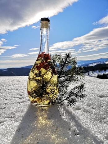 Hand holding a chilled Aqua di Monte bottle with dew drops, set against snowy mountain slopes.