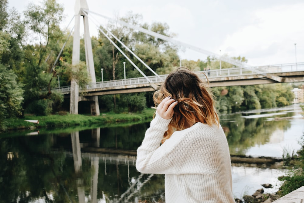 woman in white sweater standing on bridge during daytime