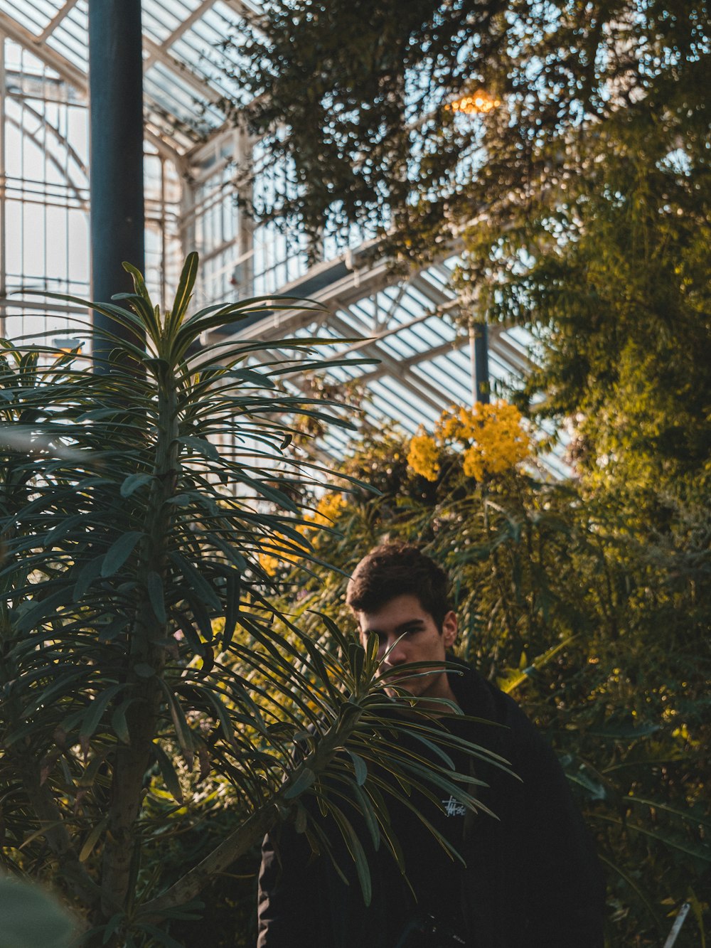 man in black jacket standing near green plants during daytime