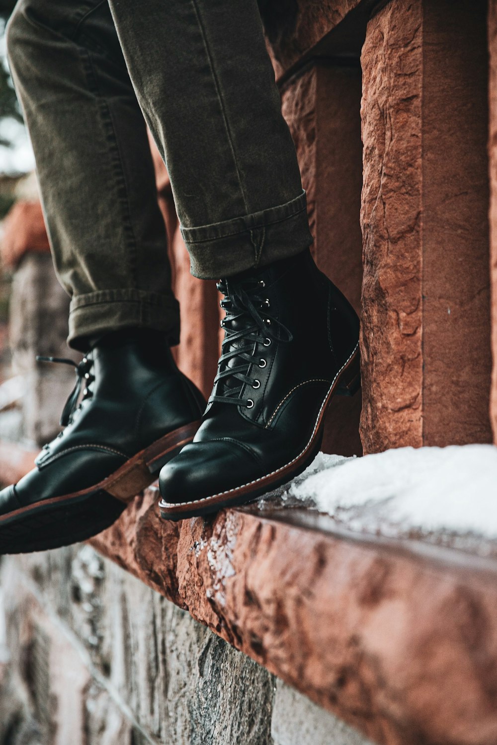 person in black leather boots standing on snow covered ground