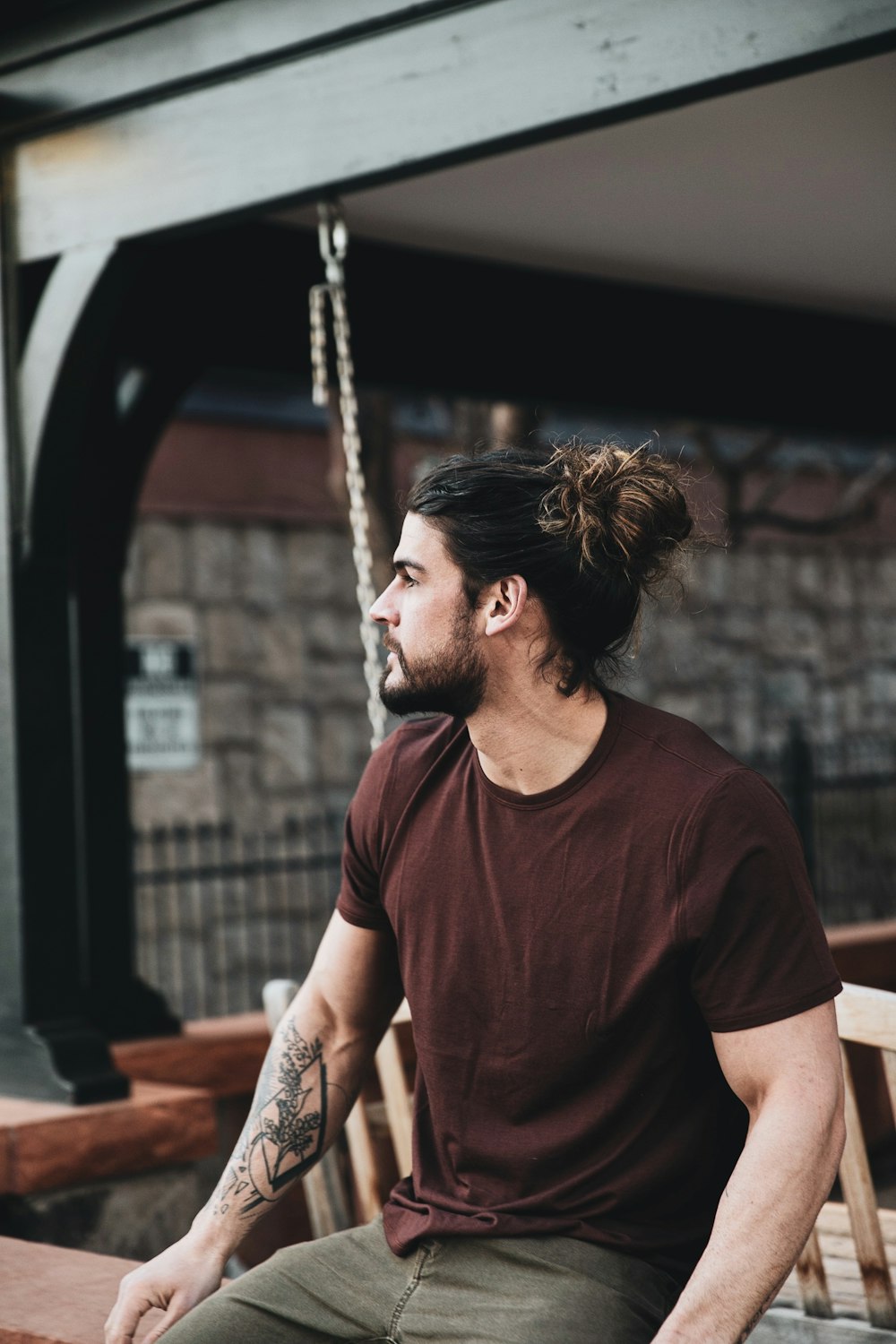 man in red crew neck t-shirt sitting on swing during daytime