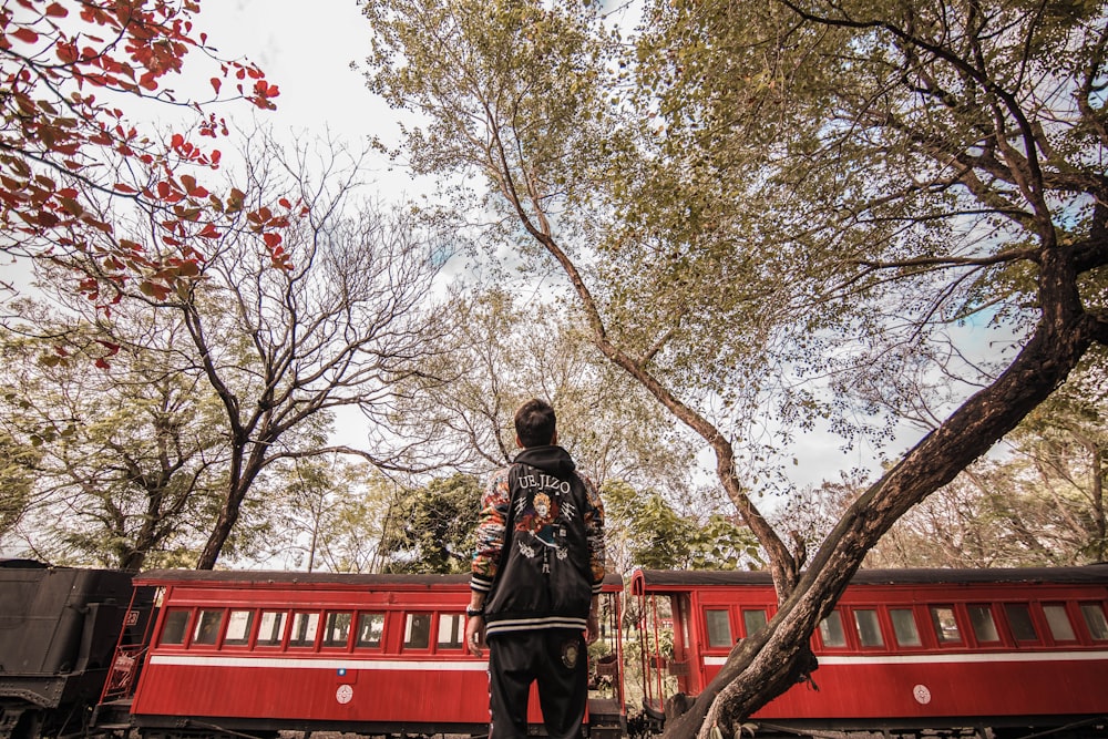 man in black jacket standing on red wooden bridge during daytime