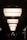 A series of large, rectangular light fixtures hang in a symmetrical arrangement along a hallway with an arched ceiling. The soft, diffused lighting creates a contrast with the dark surroundings, casting shadows on the walls. Silhouetted figures can be seen walking through the corridor, adding a sense of mystery and movement to the scene.