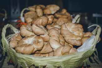 Golden crusty bolillos stacked in a basket with a warm bakery background