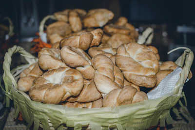 Golden crusty bolillos stacked in a basket with a warm bakery background
