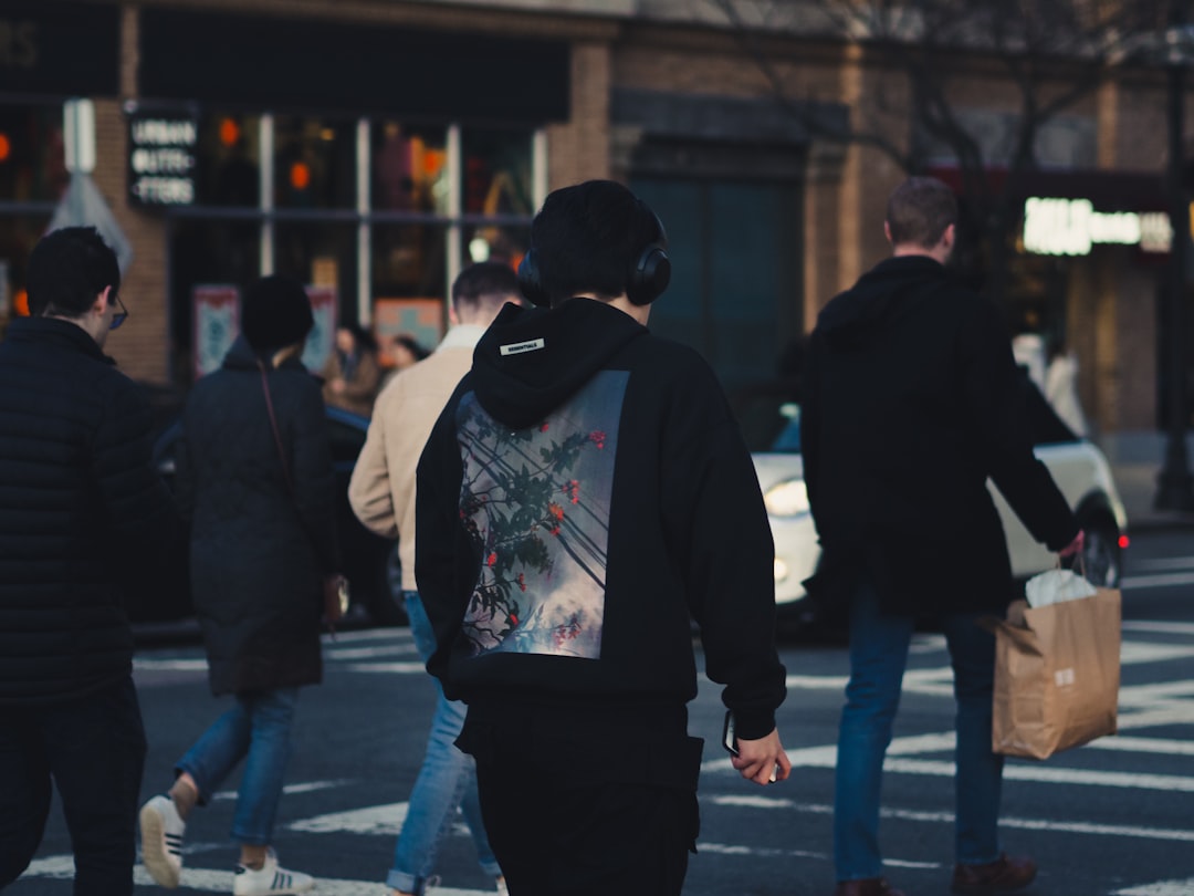 man in black and white hoodie walking on street during daytime