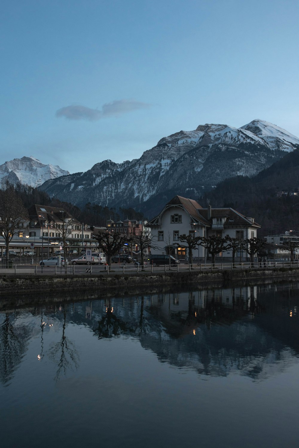 Casa bianca e marrone vicino allo specchio d'acqua e alla montagna durante il giorno