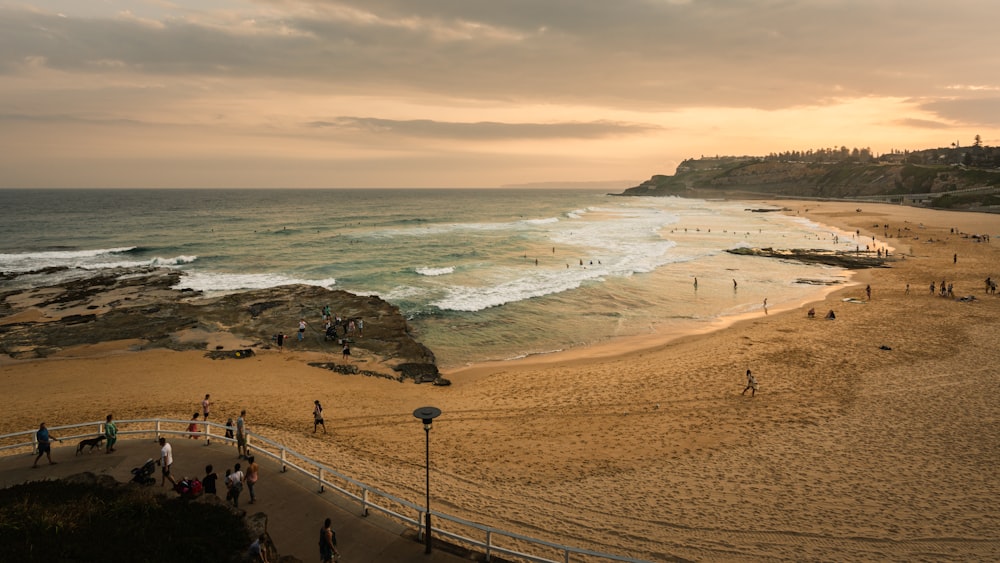 Gente caminando en la playa durante la puesta del sol