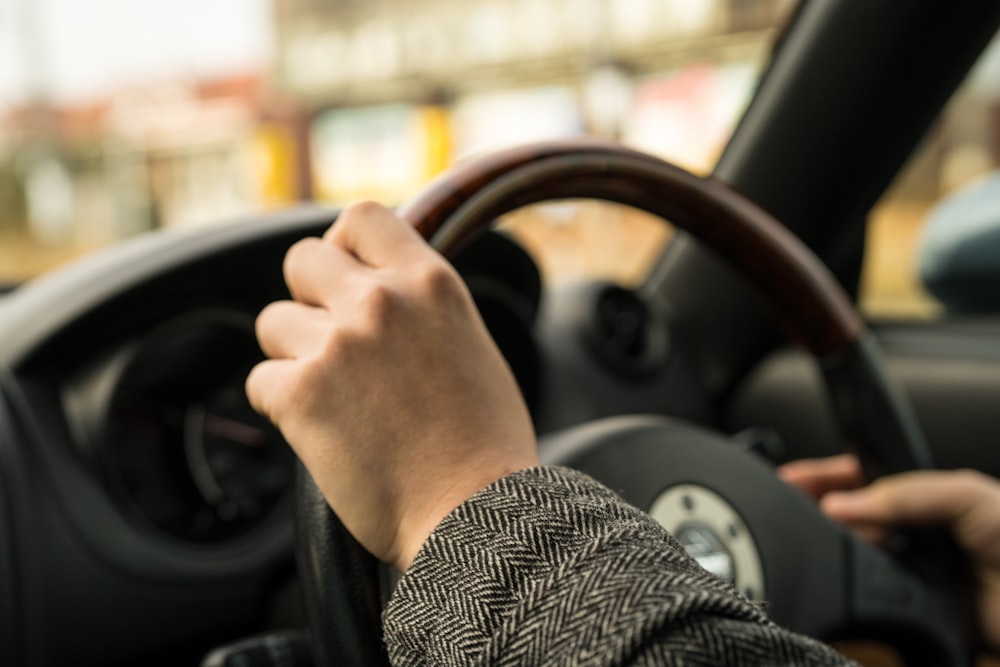 personne en noir et blanc chemise à manches longues conduisant une voiture